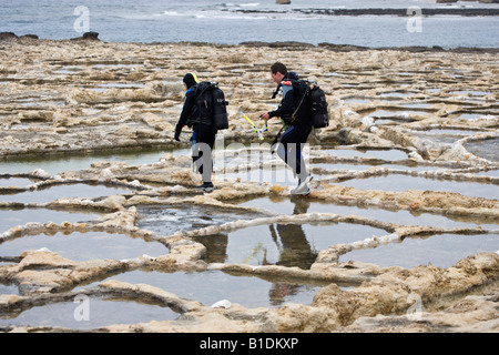 Divers walking across Salt Pans Malta Stock Photo