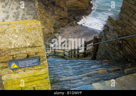 A sign warns of a steep, slippery, stone staircase at Tintagel Castle, in Cornwall, England. Stock Photo