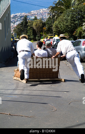 dh Tourist toboggan ride sledge MONTE FUNCHAL MADEIRA PORTUGAL Backview of downhill wicker basket tourists sleigh Stock Photo