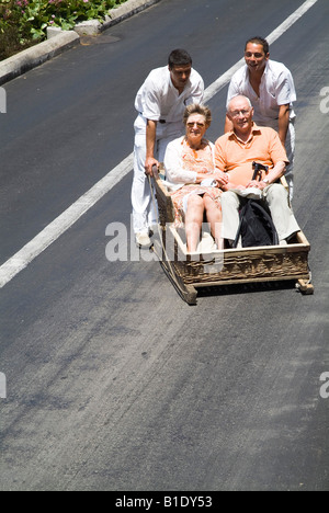 dh Basket toboggan ride MONTE FUNCHAL MADEIRA PORTUGAL Sledge tourist couple on wicker sled holiday makers sleigh Stock Photo