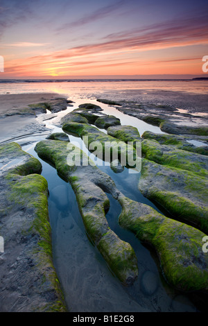 Sunset over strange rock formations on the beach at Westward Ho! Devon England Stock Photo