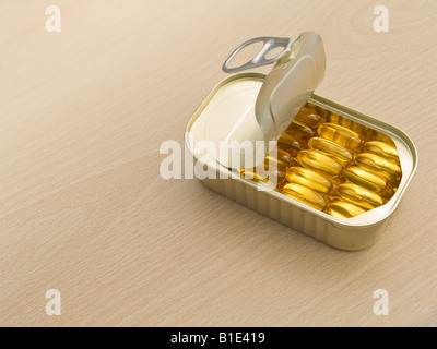 Fish oil capsules neatly arranged in a ring pull tin on a wooden table surface Stock Photo