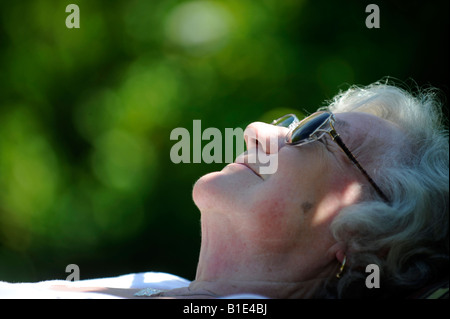 A  BRITISH OLD  LADY PENSIONER ENJOYS A SUNNY DAY SUNBATHING SLEEPING IN RETIREMENT RELAXING CONTENT,UK,ENGLAND. Stock Photo