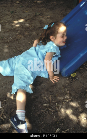 Upset nursery school child at the bottom of a slide Stock Photo