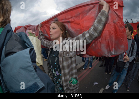 Woman marcher carries large red flag held in arms above head in anti-war march in London. Stock Photo