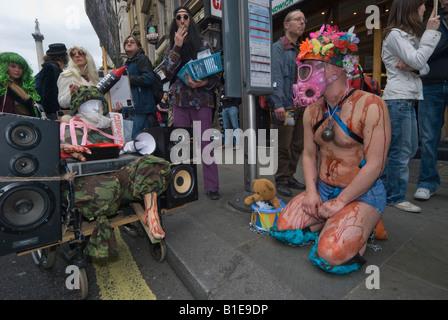 Sound system with military dummy, man smeared with blood, flower hat, pink gas mask and teddy bear at bus stop in Whitehall Stock Photo