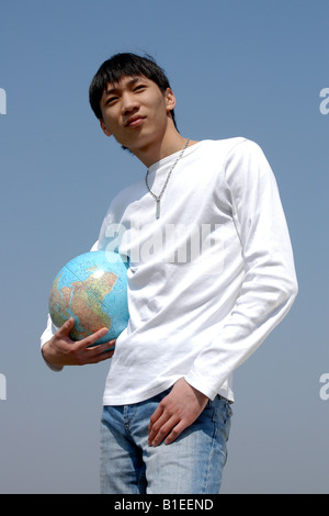 Young Asian man holding a terrestrial globe Stock Photo