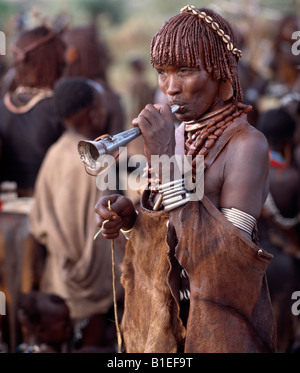 Hamar women dance, sing and blow small tin trumpets during a 'Jumping of the Bull' ceremony. Stock Photo
