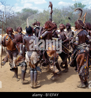 Hamar women dance, sing and blow small tin trumpets during a 'Jumping of the Bull' ceremony. Stock Photo