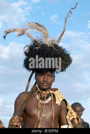 In the early morning, a Dassanech man puts on his serval cat skin cape and ostrich-feather headdress to participate. Stock Photo