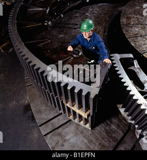 Metal worker checks quality control tolerances on the teeth of large gears in a metal fabrication plant. Stock Photo