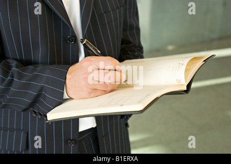 Mid section view of a businessman writing in a diary Stock Photo