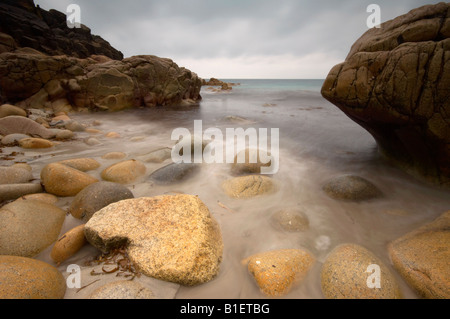 Waves rushing in over large boulders on the sssi beach at Porth nanven near St Just Cornwall UK Stock Photo