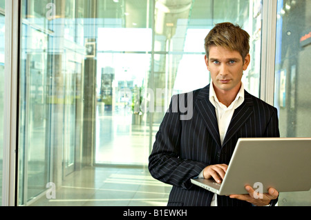 Businessman standing and using a laptop at an airport Stock Photo