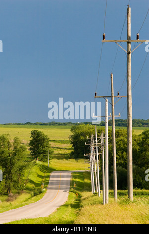 A rural road heads into the rolling hills of northern Illinois as the sun shines after a thunderstorm has passed. Stock Photo