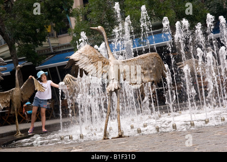 A little girl has fun in the Dancing Brolga Fountain by Terrance Plowright Cockle Bay Darling Harbour Sydney Stock Photo