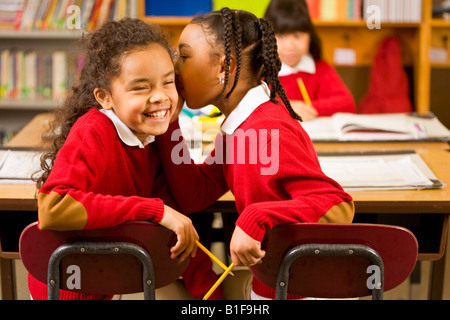 African girls telling secret in classroom Stock Photo
