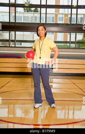 African female gym teacher holding ball Stock Photo