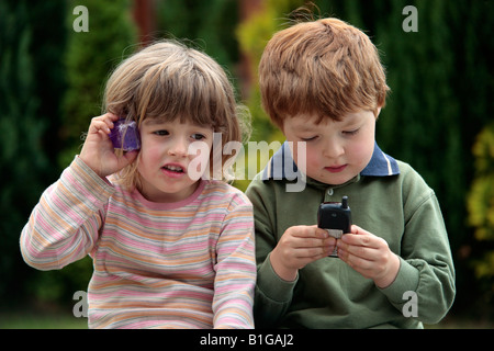 young girl and young boy playing with toy mobile phones Stock Photo