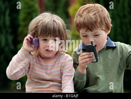 young girl and young boy playing with toy mobile phones Stock Photo