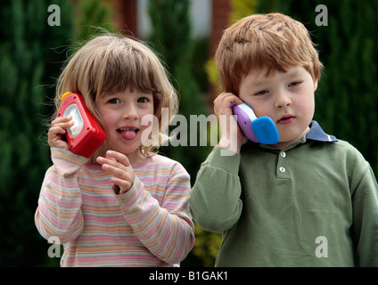 young girl and young boy playing with toy mobile phones Stock Photo