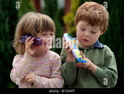 young girl and young boy playing with toy mobile phones Stock Photo