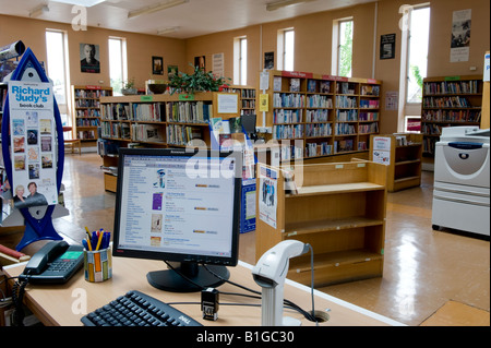 Branch library interior, community resource & facility (computer screen, staff counter, bookcases, shelves of books) - Baildon, Yorkshire, England UK. Stock Photo