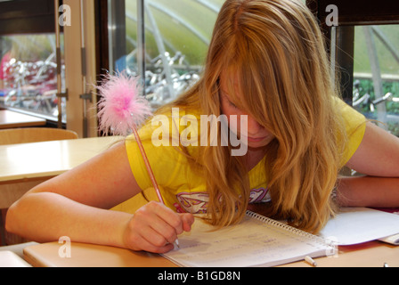 student in class writing in her notebook with fluffy pen Stock Photo