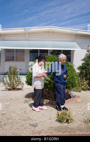 Senior Hispanic woman guides her husband as they walk from their trailer Stock Photo