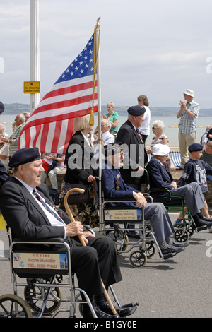 American VFW with the Stars and stripes is pushed in his wheelchair at a summer parade Stock Photo