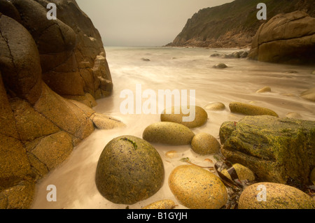 Waves washing in around large boulders on the sssi beach at Porth Nanven St Just Cornwall UK Stock Photo