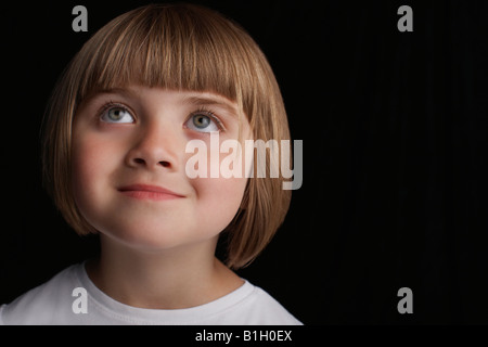 Girl (5-6) on black background, portrait, close-up Stock Photo