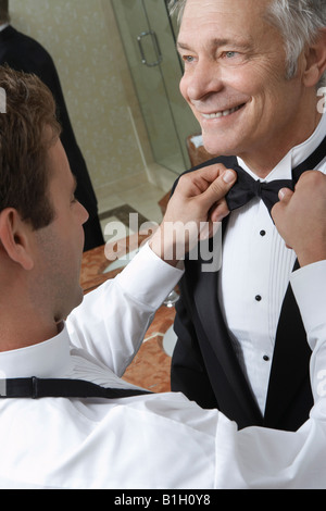 Young man tying middle-aged man's bow tie Stock Photo