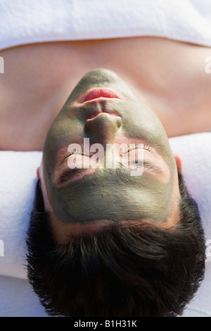 Young woman wearing mud facial mask at health spa, close-up Stock Photo