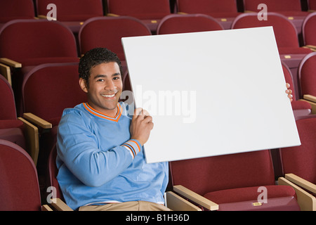 Man sitting in auditorium, holding empty placard Stock Photo