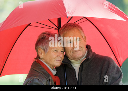 Senior couple using a red umbrella Stock Photo
