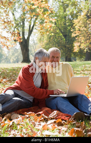 Senior couple using a laptop in a park Stock Photo