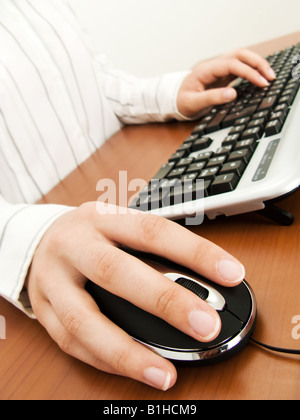 Businesswoman typing in the computer keyboard and using a mouse Stock Photo