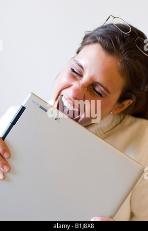 young woman biting on her laptop in frustration Stock Photo