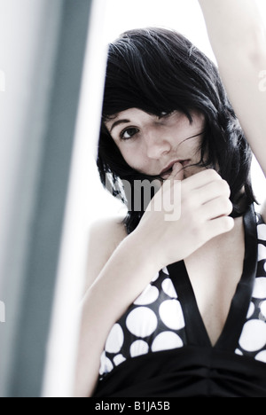 young woman wearing a black and white dress, looking shy Stock Photo