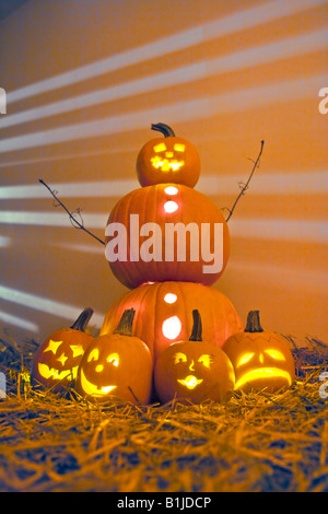 Jack-O-Lantern man with smaller Jack-O-Lanterns on the ground in front of him in hay on the ground. Stock Photo