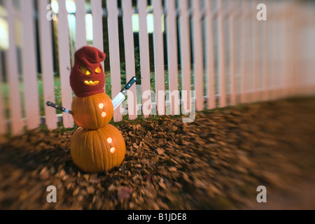 Burgler Jack-O-Lantern man standing wearing a stocking mask with steak knifes as arms in front of a white picktet fence Stock Photo