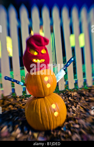 Burgler Jack-O-Lantern man standing wearing a stocking mask with steak knifes as arms in front of a white picktet fence Stock Photo