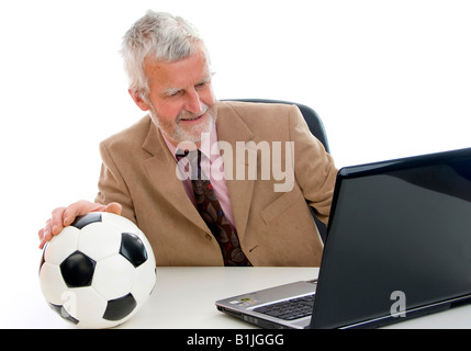 older businessman with football using laptop Stock Photo