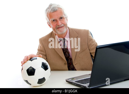 older businessman with football using laptop Stock Photo