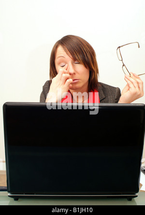young businesswoman with tired eyes using laptop Stock Photo