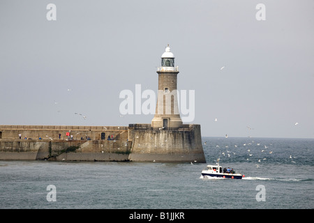 The lighthouse on the north pier of the Tyne as seen from South Shields, England. A boat comes into the mouth of the river. Stock Photo