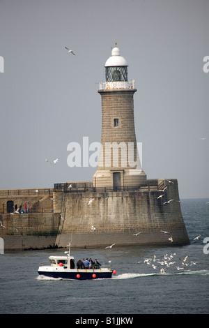 The lighthouse on the north pier of the Tyne as seen from South Shields, England. A boat comes into the mouth of the river. Stock Photo