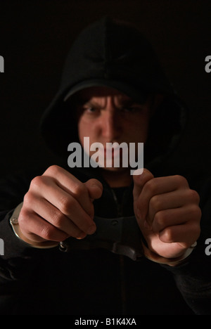 Handcuffed youth wearing black hoody Stock Photo