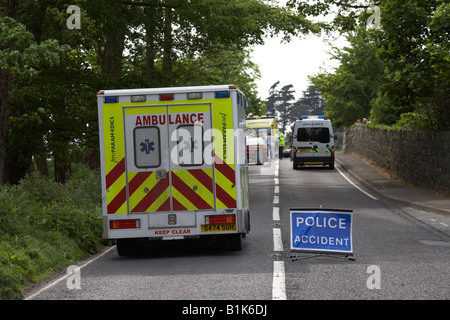 paramedic private ambulance passes police accident temporary sign in the middle of the road at the scene of a road accident Stock Photo